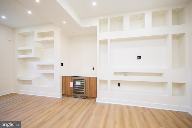 unfurnished living room with bar, wine cooler, light hardwood / wood-style flooring, and built in features