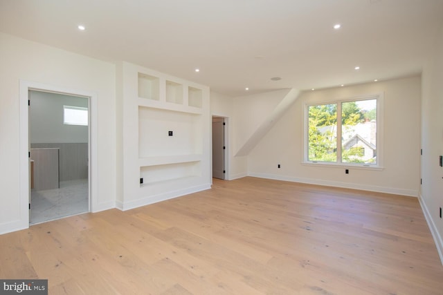 unfurnished living room featuring built in features and light wood-type flooring