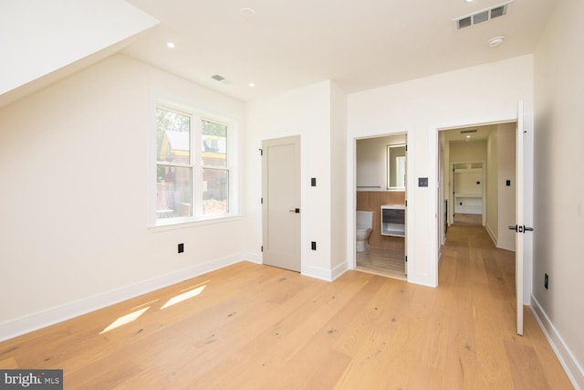 unfurnished bedroom featuring light wood-type flooring and connected bathroom