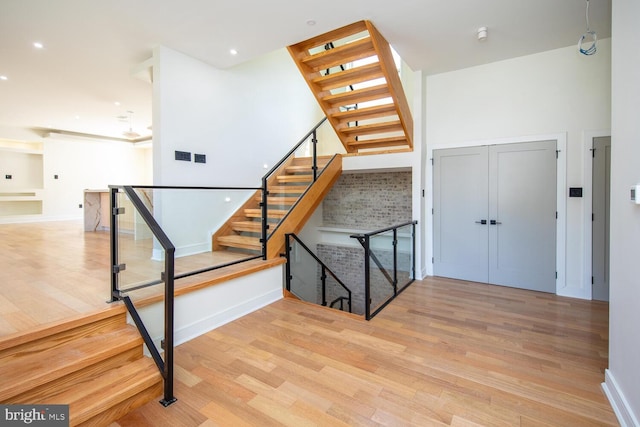 staircase featuring a towering ceiling and wood-type flooring