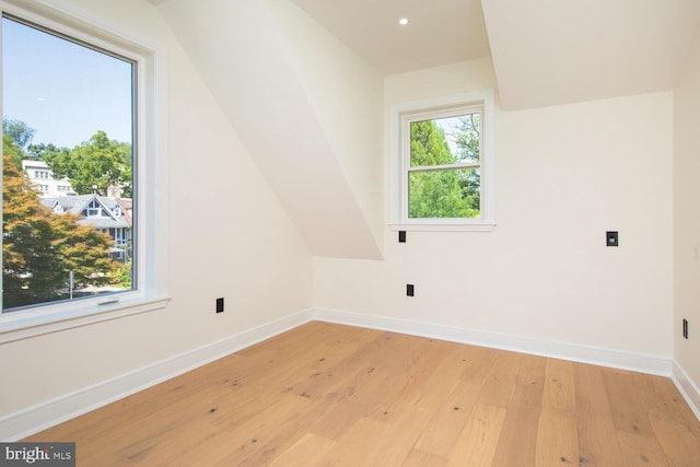 additional living space with light hardwood / wood-style flooring and lofted ceiling