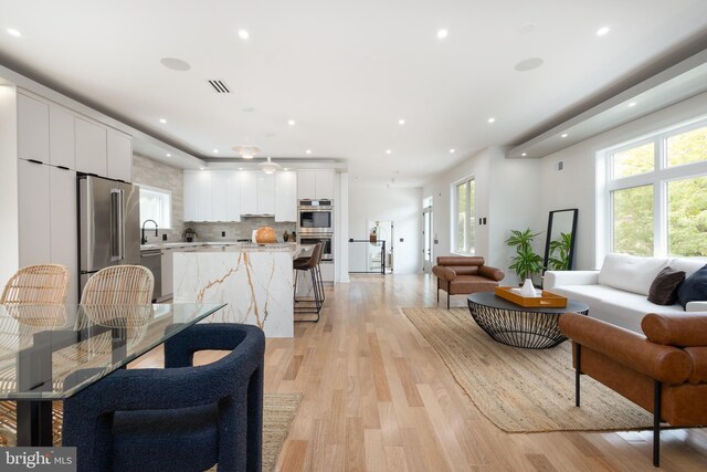 kitchen featuring light hardwood / wood-style flooring, white cabinetry, light stone counters, and stainless steel appliances