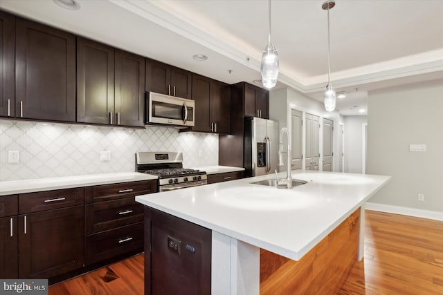 kitchen with a center island with sink, pendant lighting, dark brown cabinets, and stainless steel appliances