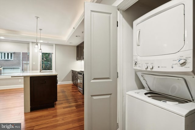 laundry room with stacked washer / dryer, dark wood-type flooring, and sink