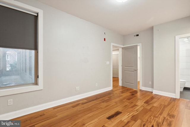 unfurnished bedroom with wood-type flooring and ensuite bath