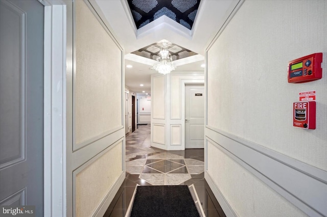 corridor with crown molding, tile patterned flooring, and a chandelier