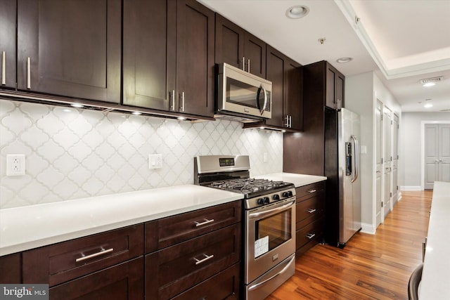 kitchen featuring dark brown cabinets, dark wood-type flooring, tasteful backsplash, and appliances with stainless steel finishes