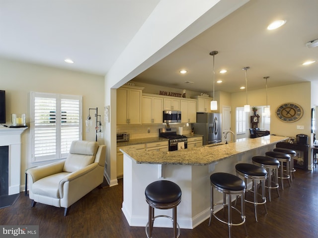 kitchen featuring a kitchen breakfast bar, a large island with sink, backsplash, and stainless steel appliances