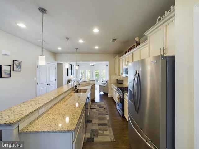 kitchen with a large island with sink, dark hardwood / wood-style flooring, appliances with stainless steel finishes, light stone counters, and sink