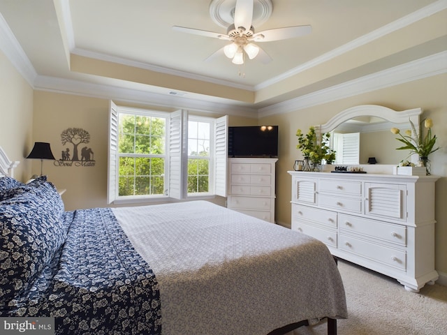 bedroom featuring ceiling fan, ornamental molding, light carpet, and a tray ceiling