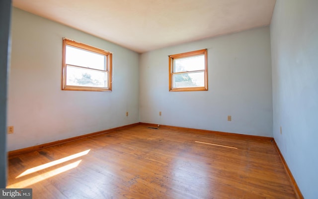 spare room featuring wood-type flooring and a healthy amount of sunlight