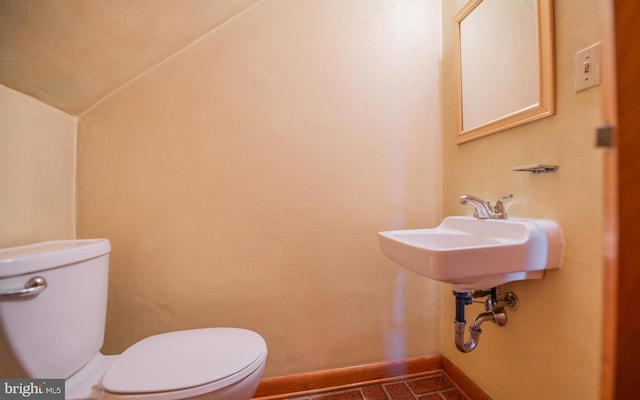 bathroom with toilet and lofted ceiling