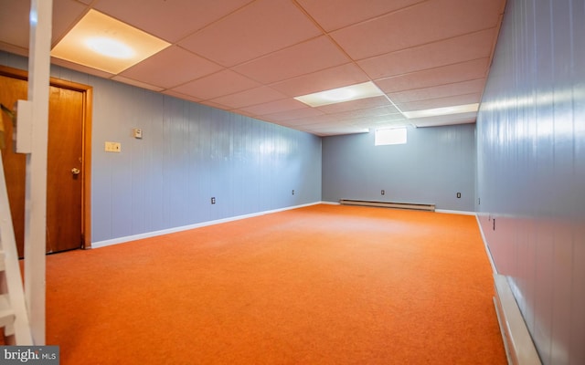 basement featuring a paneled ceiling, baseboard heating, and carpet flooring