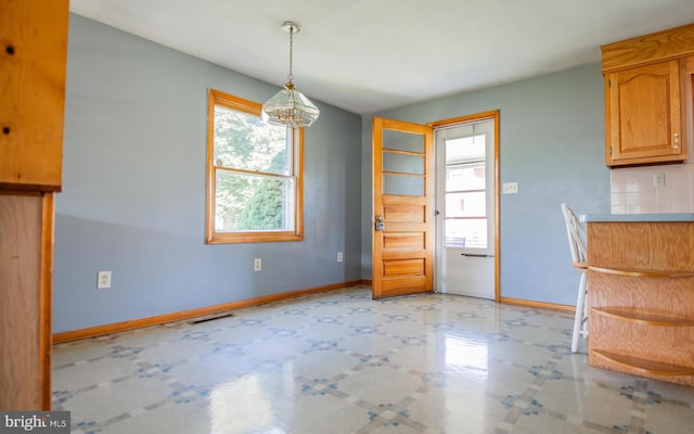 unfurnished dining area featuring a notable chandelier