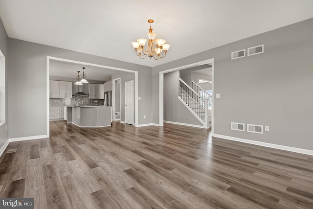 unfurnished living room featuring an inviting chandelier and hardwood / wood-style floors