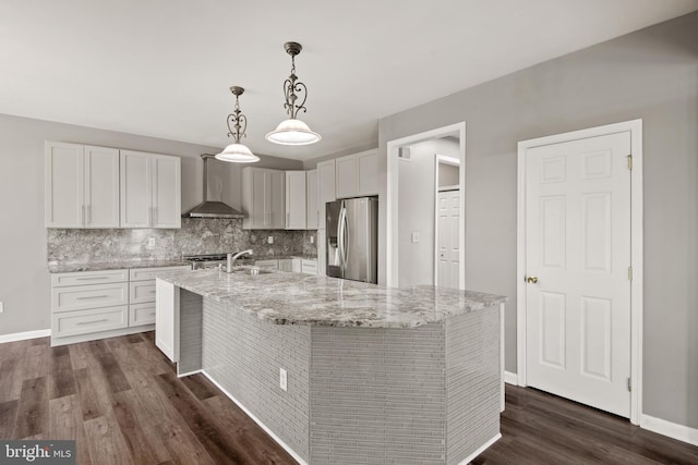 kitchen featuring white cabinetry, an island with sink, sink, stainless steel refrigerator with ice dispenser, and wall chimney range hood