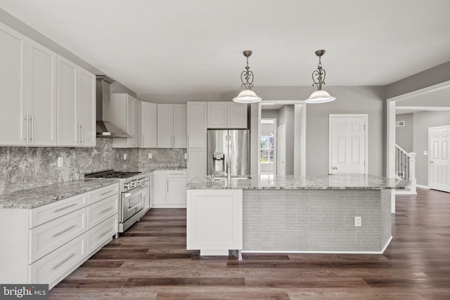 kitchen with wall chimney exhaust hood, white cabinetry, a center island, hanging light fixtures, and stainless steel appliances