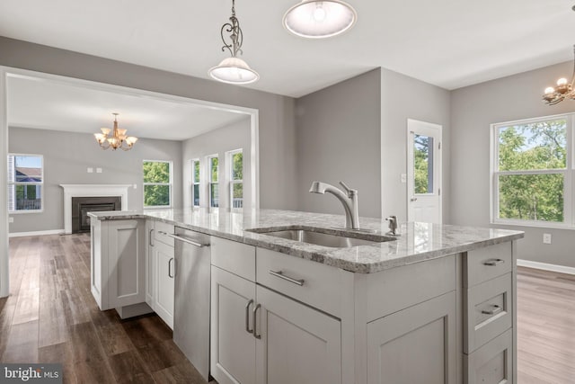 kitchen with sink, a notable chandelier, and light stone countertops