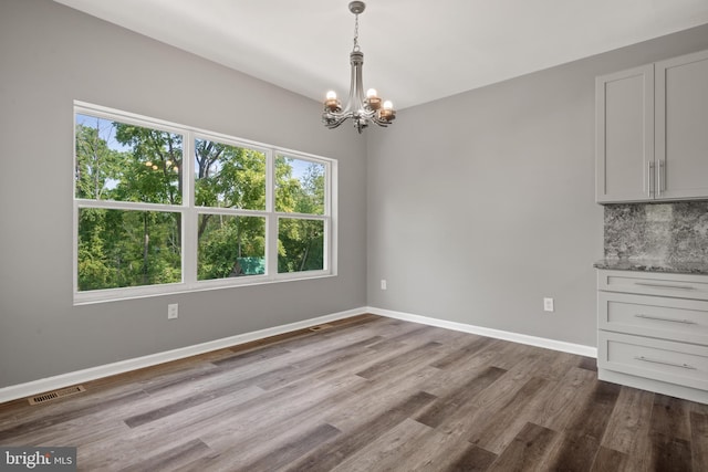 unfurnished dining area featuring wood-type flooring and a chandelier