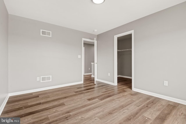 unfurnished bedroom with a spacious closet, light hardwood / wood-style floors, and a closet