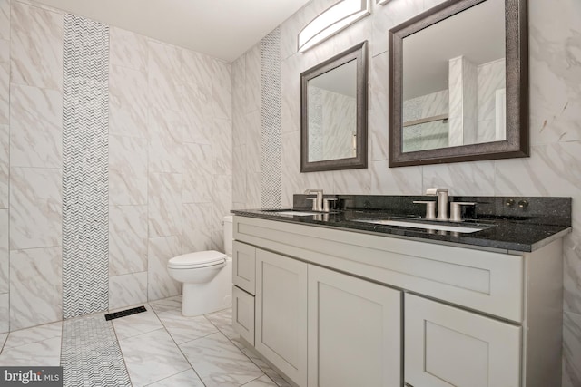 bathroom with vanity, toilet, and tile walls