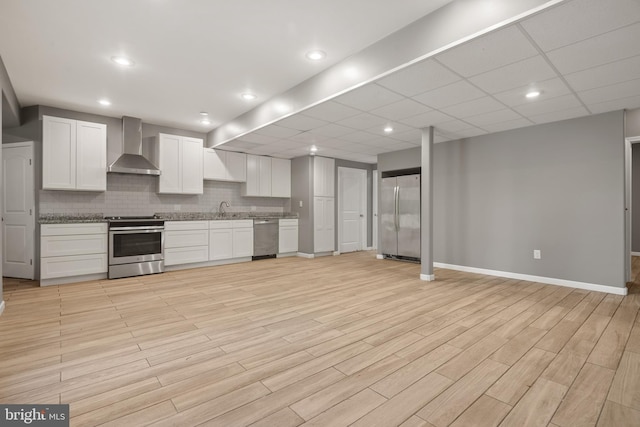 kitchen featuring wall chimney exhaust hood, sink, white cabinetry, tasteful backsplash, and stainless steel appliances