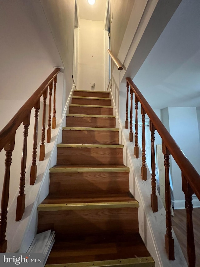 staircase with wood-type flooring and a high ceiling