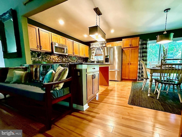 kitchen with decorative light fixtures, light hardwood / wood-style flooring, stainless steel appliances, and a center island