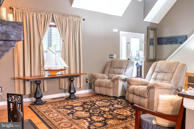 living area featuring hardwood / wood-style floors and lofted ceiling with skylight