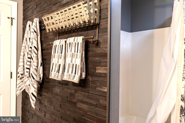 bathroom featuring shower / tub combo with curtain and wood walls