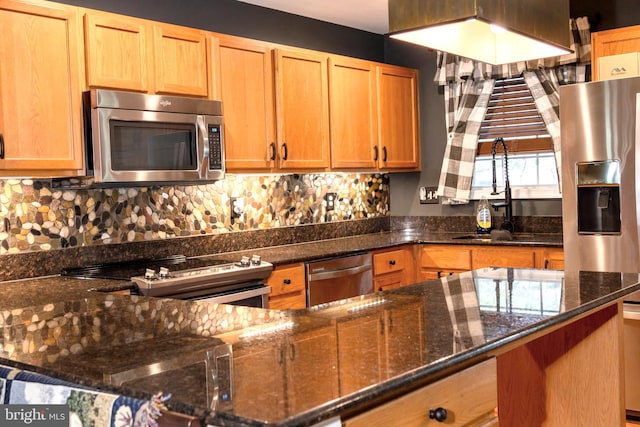 kitchen featuring appliances with stainless steel finishes, sink, decorative backsplash, and dark stone countertops