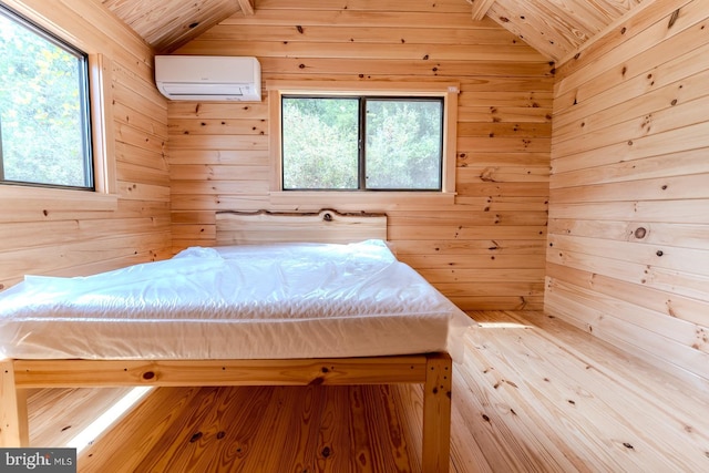 unfurnished bedroom featuring vaulted ceiling, an AC wall unit, wood walls, and multiple windows