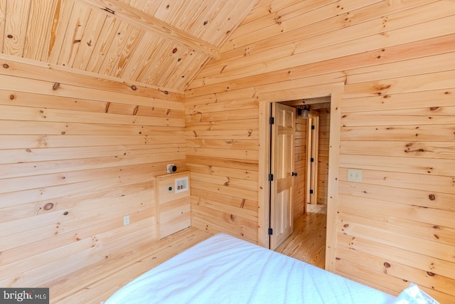 bedroom with lofted ceiling, wooden ceiling, wooden walls, and light wood-style floors