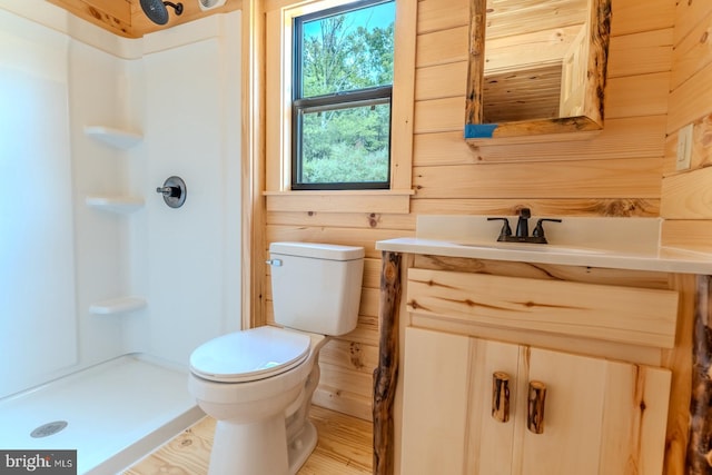 bathroom with a stall shower, wood walls, vanity, and toilet