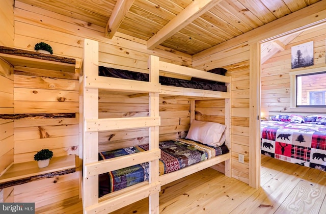 bedroom with beam ceiling, a sauna, wooden walls, wood finished floors, and wooden ceiling