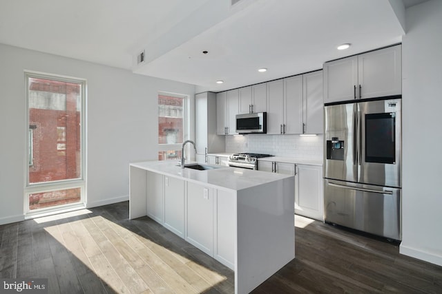 kitchen with sink, appliances with stainless steel finishes, backsplash, and hardwood / wood-style floors