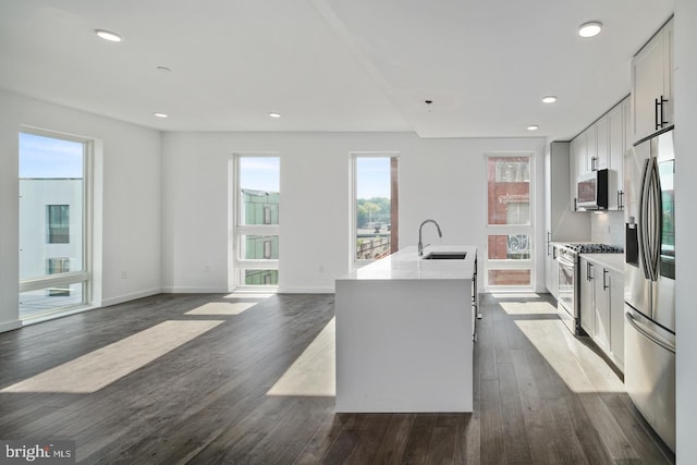 kitchen featuring range, a center island with sink, dark hardwood / wood-style floors, refrigerator, and white cabinetry