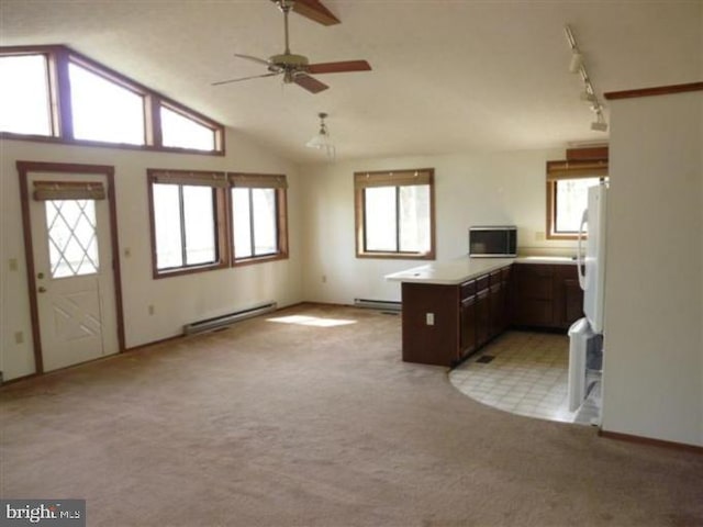 kitchen with kitchen peninsula, a wealth of natural light, vaulted ceiling, and baseboard heating