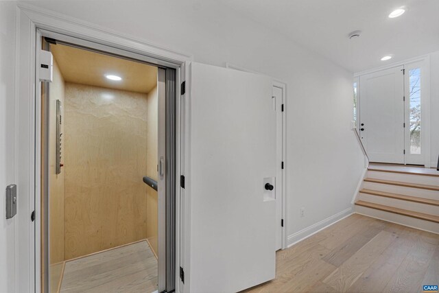 hallway featuring elevator and light hardwood / wood-style floors