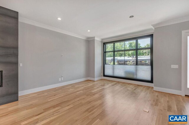 spare room featuring ornamental molding and light hardwood / wood-style flooring