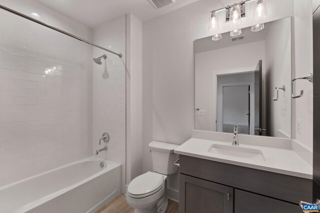 full bathroom featuring vanity, toilet, tiled shower / bath combo, and wood-type flooring