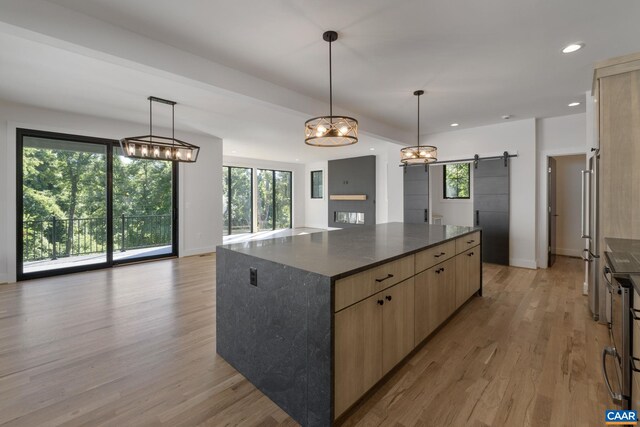 kitchen featuring a kitchen island, a barn door, dark stone countertops, and decorative light fixtures