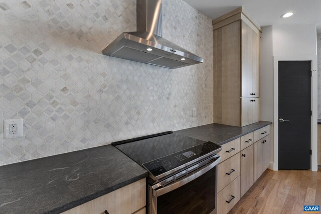 kitchen featuring light hardwood / wood-style flooring, light brown cabinetry, stainless steel range with electric cooktop, and wall chimney range hood