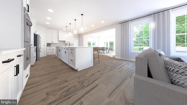 kitchen with white cabinets, plenty of natural light, and a kitchen island with sink