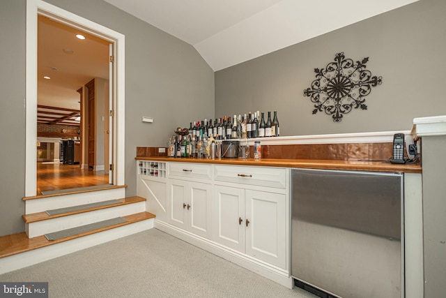 bar featuring white cabinetry, lofted ceiling, light carpet, and refrigerator