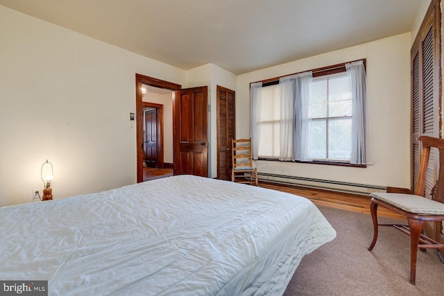 bedroom featuring a baseboard heating unit and hardwood / wood-style floors