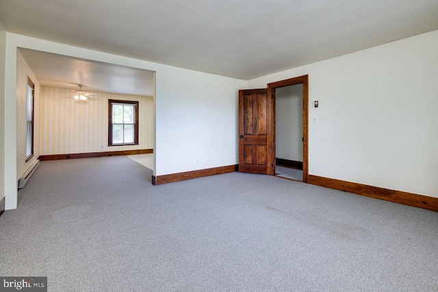 empty room featuring baseboard heating and carpet