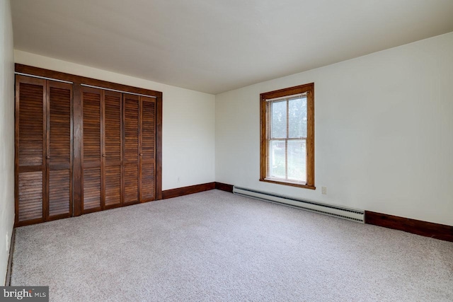 unfurnished bedroom featuring carpet floors and a baseboard heating unit