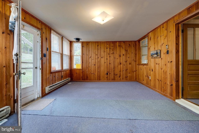 carpeted empty room with a baseboard heating unit and wood walls