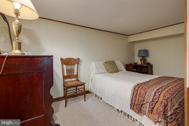 carpeted bedroom with ornamental molding and wooden walls